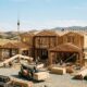 Construction crew framing a custom home with cranes and building materials on site in Southern California